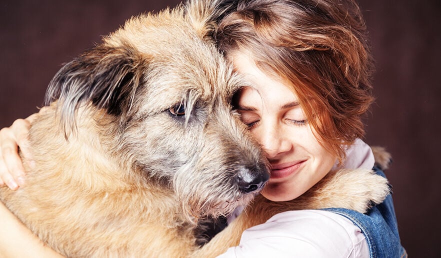 young woman with a shaggy dog on a dark background.